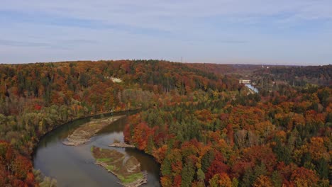 Locked-4k-aerial-shot-of-a-flowing-river-between-autumn-colored-tree-tops-at-a-wonderful-day-of-fall-in-germany