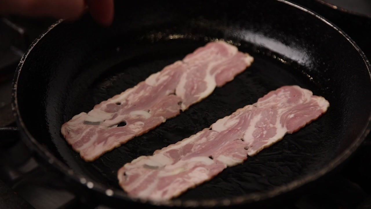 Primo piano di pancetta cruda messa in una padella