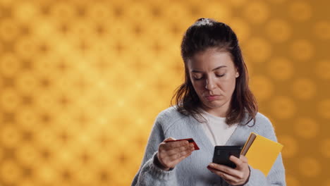 Woman-holding-books,-purchasing-more-with-phone,-studio-background