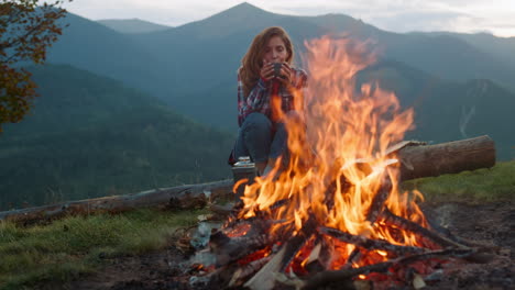 closeup relaxed woman camping on nature. tourist look bonfire in mountains trip.