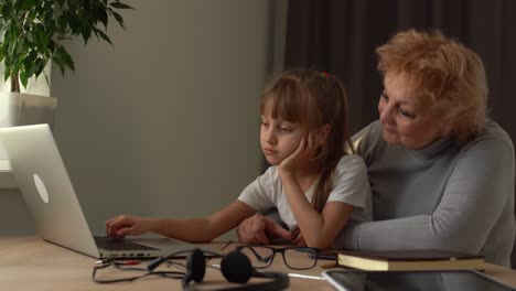 abuela y nieta triste estudian en línea en una computadora portátil