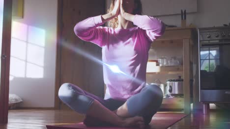 animation of light spots over caucasian woman practicing yoga and meditating