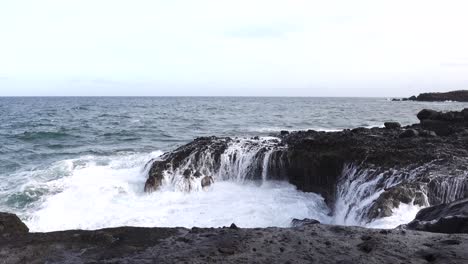 Las-Olas-Del-Mar-Rompiendo-En-Las-Rocas-A-Lo-Largo-De-La-Orilla-Del-Mar-Lanzando-Spray-En-El-Aire