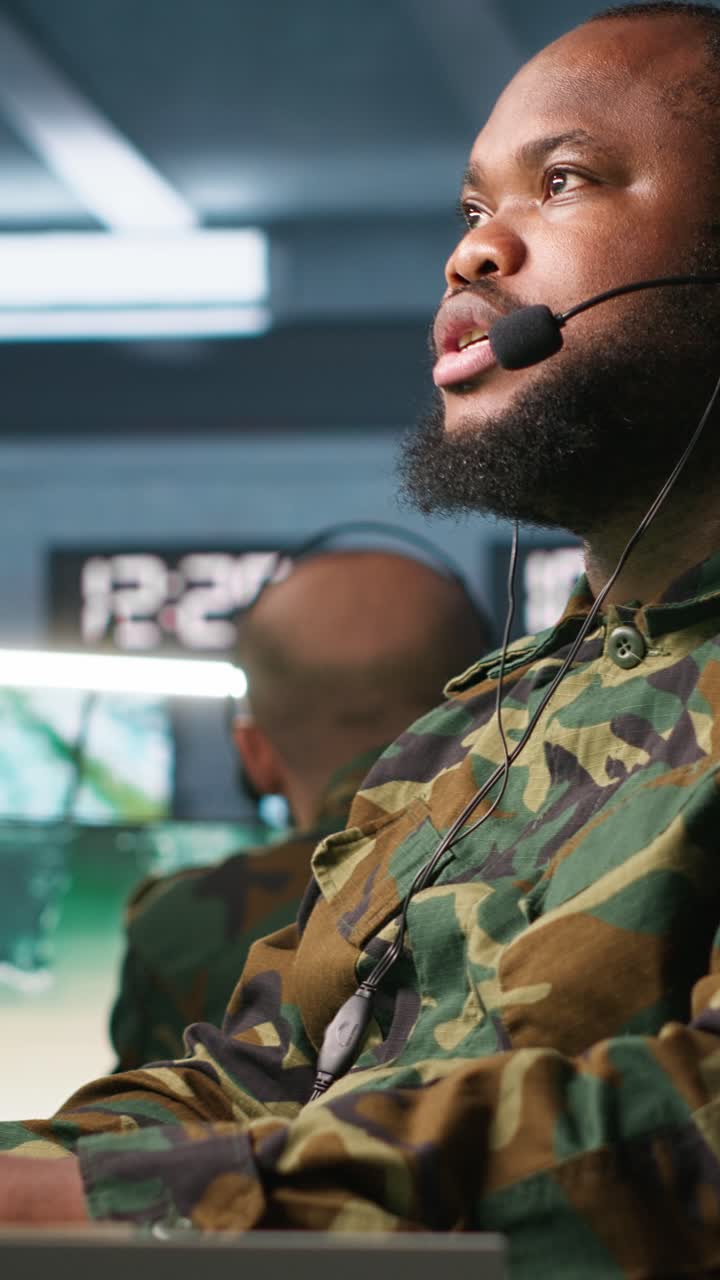 Video verticale. Operatore militare che gestisce reti di comunicazione, guardando gli schermi.