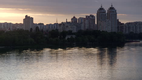 sunset cityscape at cloudy sky drone shot. calm river water reflecting building