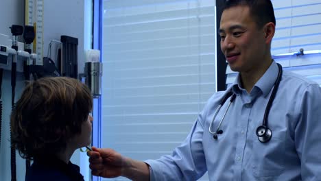 Side-view-of-young-asian-male-doctor-showing-tuning-fork-to-caucasian-boy-patient-in-clinic-4k