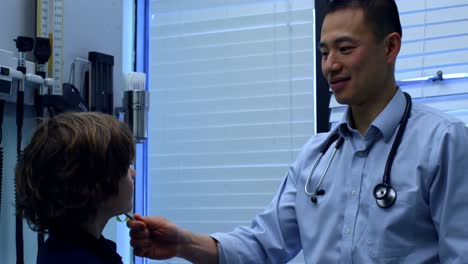 side view of young asian male doctor showing tuning fork to caucasian boy patient in clinic 4k