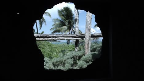 Hole-in-a-building-stone-wall,-reviling-beautiful-greenery-and-sunny-sky