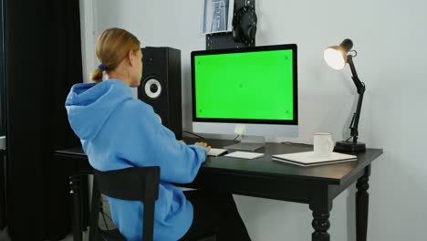 woman working at a computer with a green screen