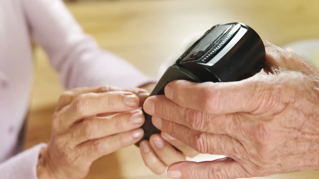 Senior woman paying the cafe bill through credit card terminal 4k
