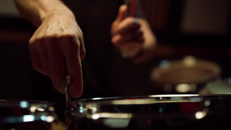 musician tuning drum kit in studio