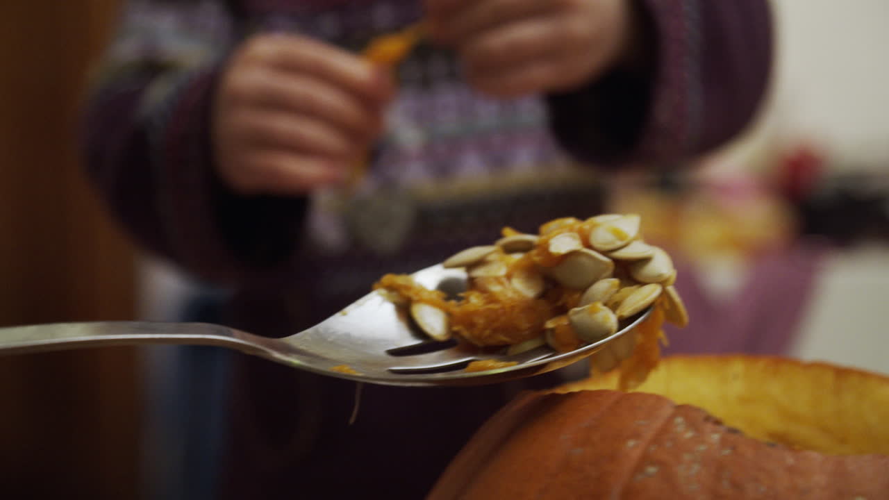 dos niños pequeños quitando las semillas de una calabaza para halloween