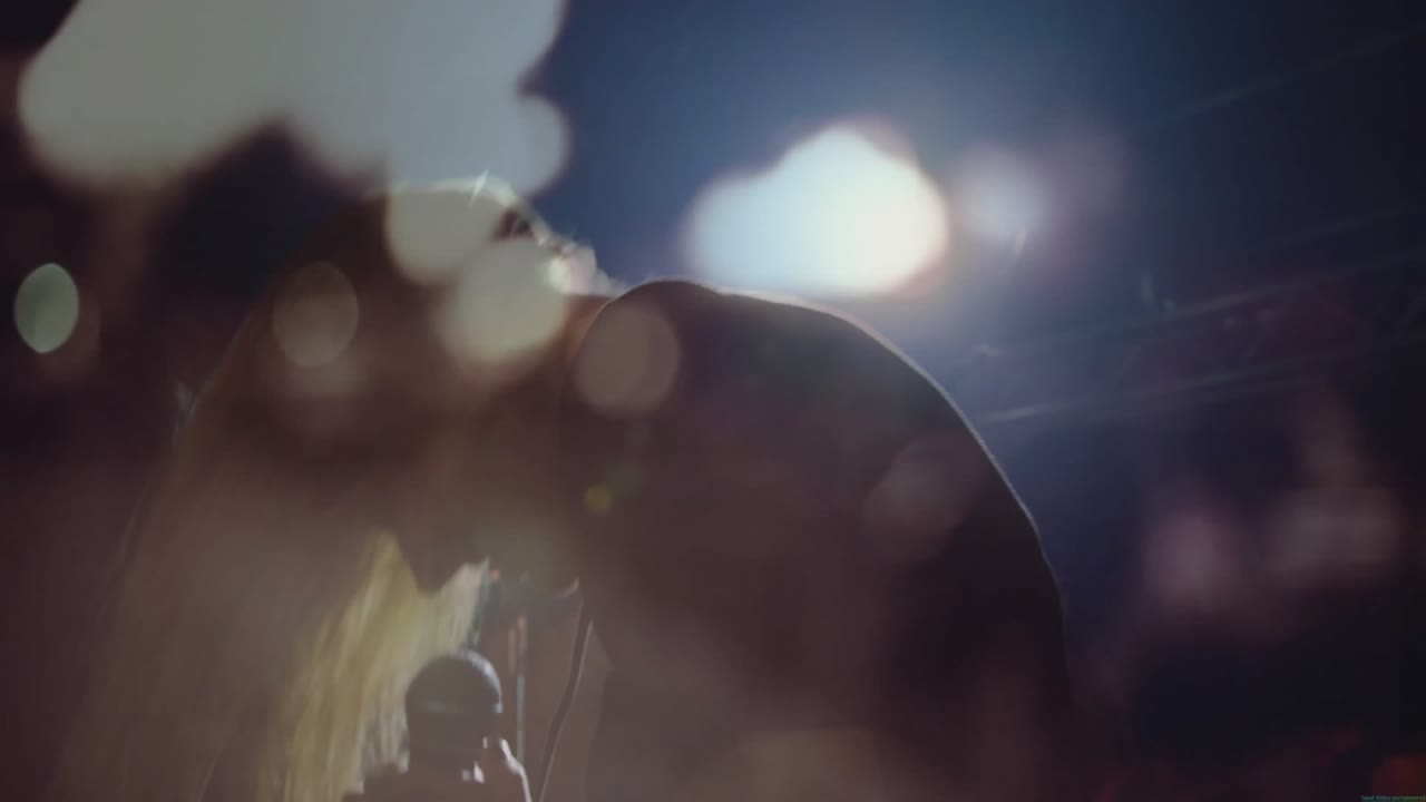 Cantora se apresentando em palco da indústria musical, com holofotes animados e gráficos de reflexo de lente.