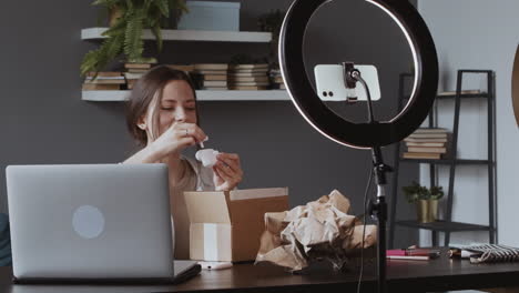 Emocionada-Mujer-Vloguera-Sacando-De-La-Caja-Que-Recibió-Por-Correo-Unos-Auriculares-De-Música-Inalámbricos-Y-Mostrándoselos-A-La-Cámara