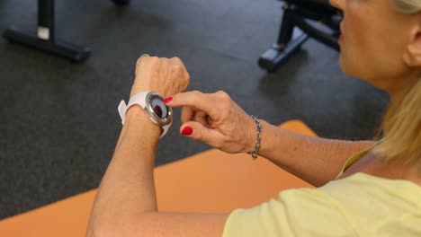 Mujer-Mayor-Revisando-Su-Reloj-Inteligente-En-El-Gimnasio-4k