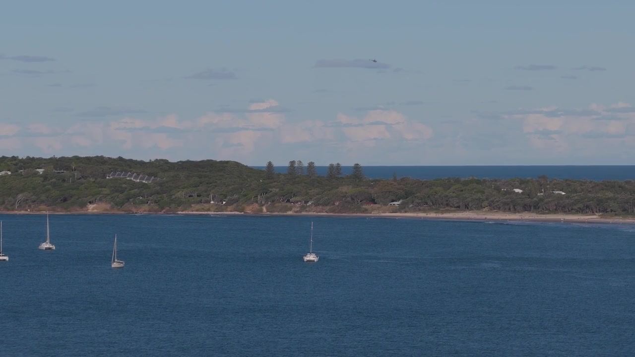 Ripresa aerea con drone in panoramica da sinistra a destra sulla spiaggia di Little Wategos e la costa vicino a Cape Byron a Byron Bay, Nuovo Galles del Sud, Australia