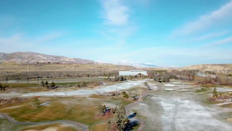 panorama of a golf course in winter with a light dusting of snow and mountains in the background