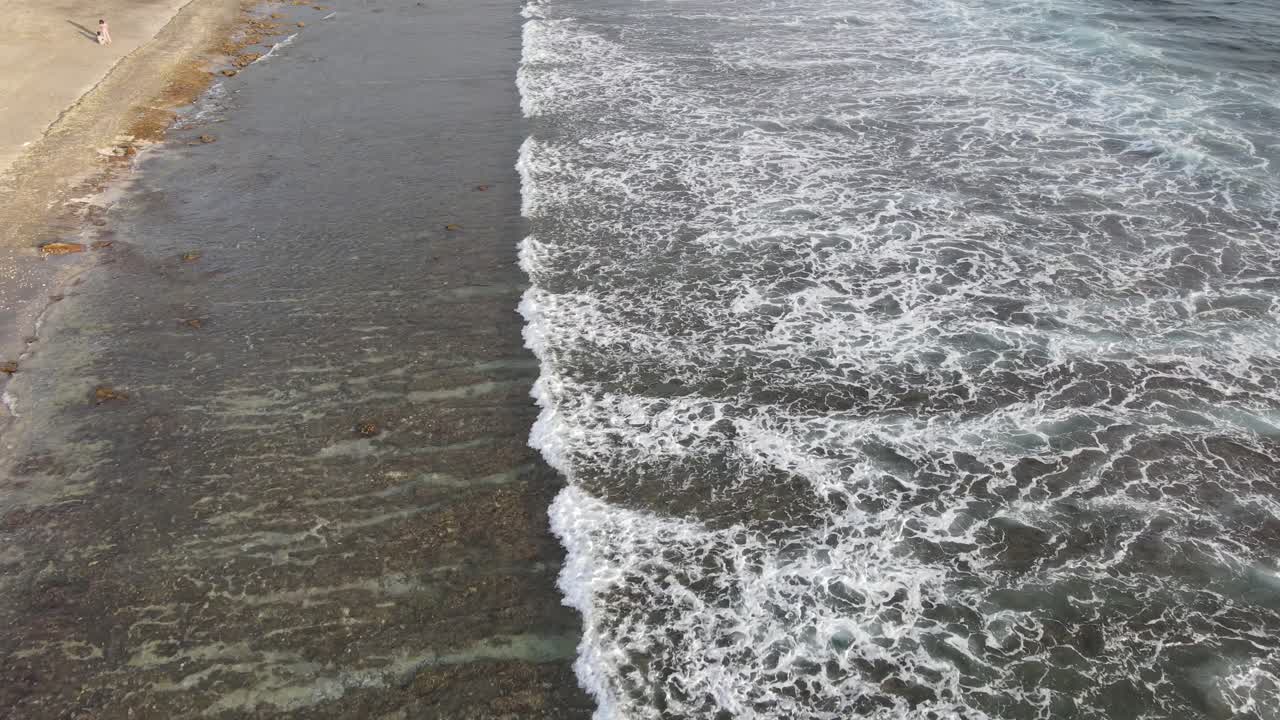 Veduta aerea di onde oceaniche che si infrangono su una costa rocciosa.