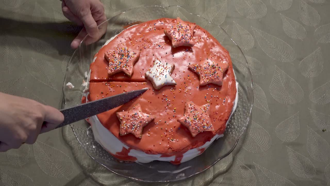 한 여인이  크림, 은 아이싱, 별과 콘티로 장식된 집에서 만든 케이크를 잘라내기 시작합니다. 회색 식탁 위에 서 있습니다. 축제 이벤트. 클로즈업. 얼굴없는.  뷰.