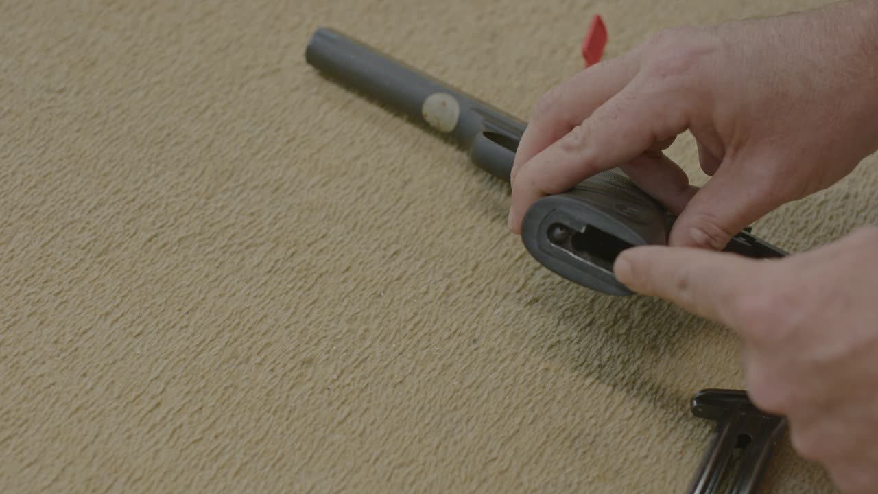 Man placing chamber flag in pistol chamber and showing the gun's magazine is removed