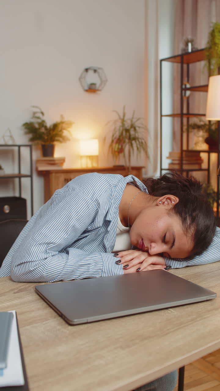 Bored sleepy young woman freelancer closing laptop and sleeping at home office desk in living room
