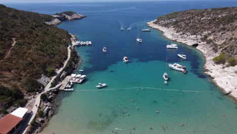 Gente-Relajándose-En-La-Playa-De-Arena-De-Porat-En-La-Isla-De-Bisevo,-Barcos-Anclados-En-Alta-Mar,-Agua-Clara-Croacia