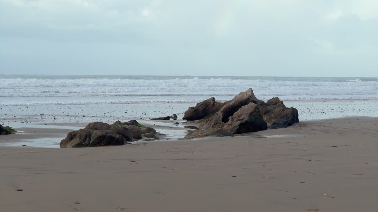 la escarpada y rocosa costa de españa está definida por las olas que se estrellan en el horizonte, capturando una tranquila vista diurna de belleza natural.