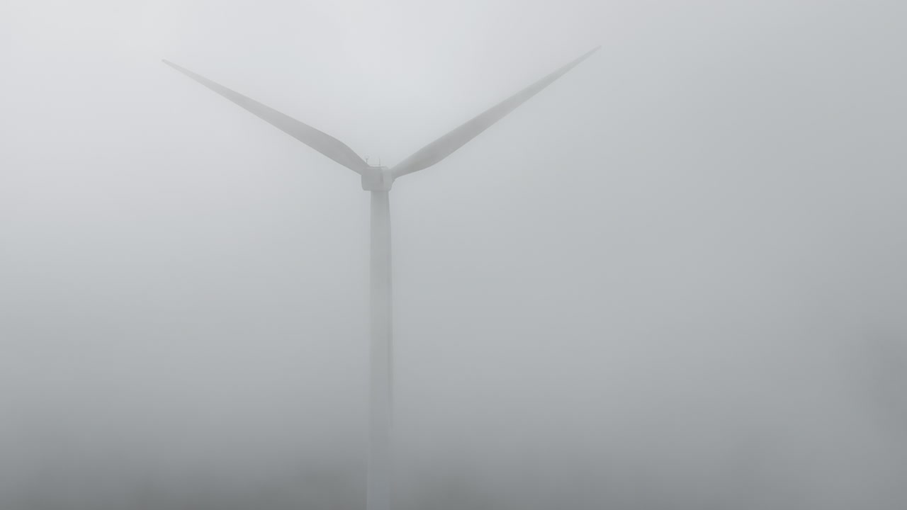 Static drone shot of wind turbines in West Yorkshire on a grey, misty and cold morning overlooking hills and fields