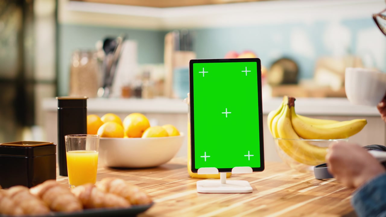 Schermo verde verticale su tablet con un adulto che lavora al tavolo della cucina