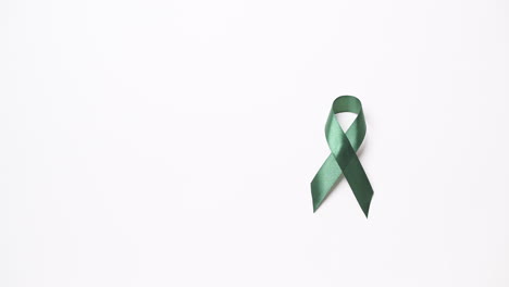 Detail-of-male-hand-putting-green-ribbon-over-white-background