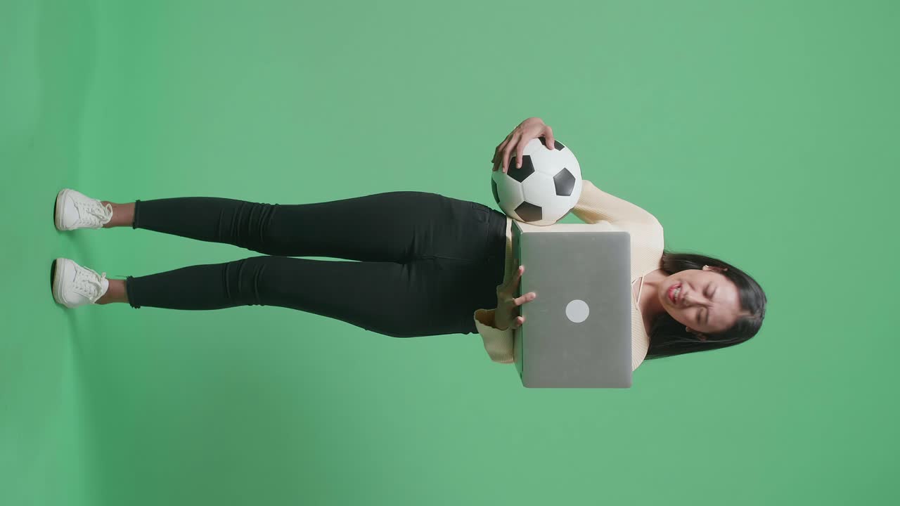 mujer con una computadora portátil y una pelota de fútbol