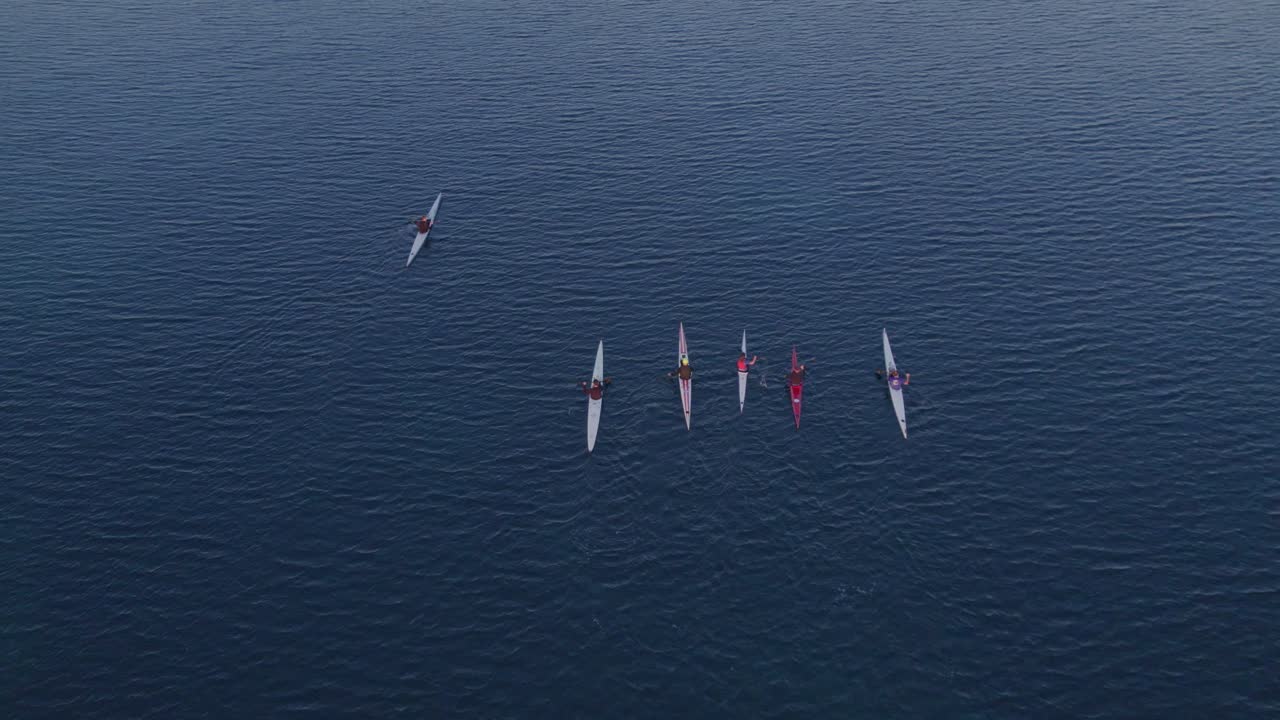 해가 지는 동안 평온한 바다에서 카야크를 타고  ⁇ 고 있는 사람들의  ⁇ 에서 내려다보는 모습