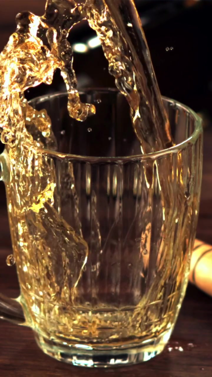Birra dorata che si versa e schizza in un boccale di vetro trasparente