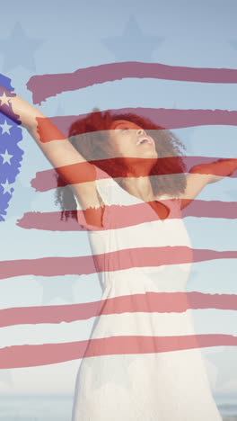 animation of american flag over african american woman raising hands at beach