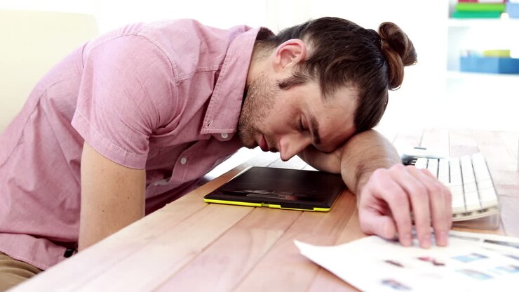 Graphic designer oberato di lavoro che dorme sulla sua scrivania