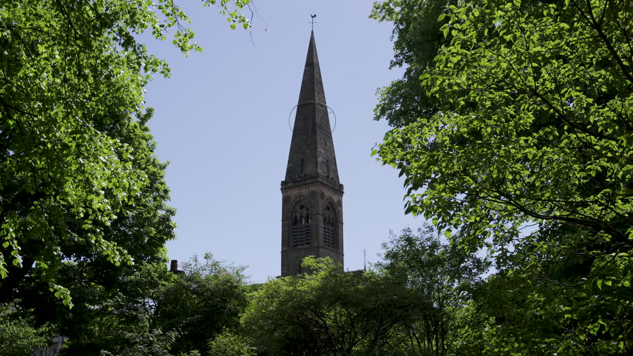 Guglia della chiesa di Oran Mor a Glasgow, circondata da alberi verdi in estate