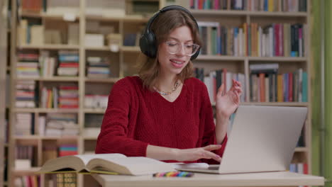 mujer joven escuchando audio con auriculares en la biblioteca