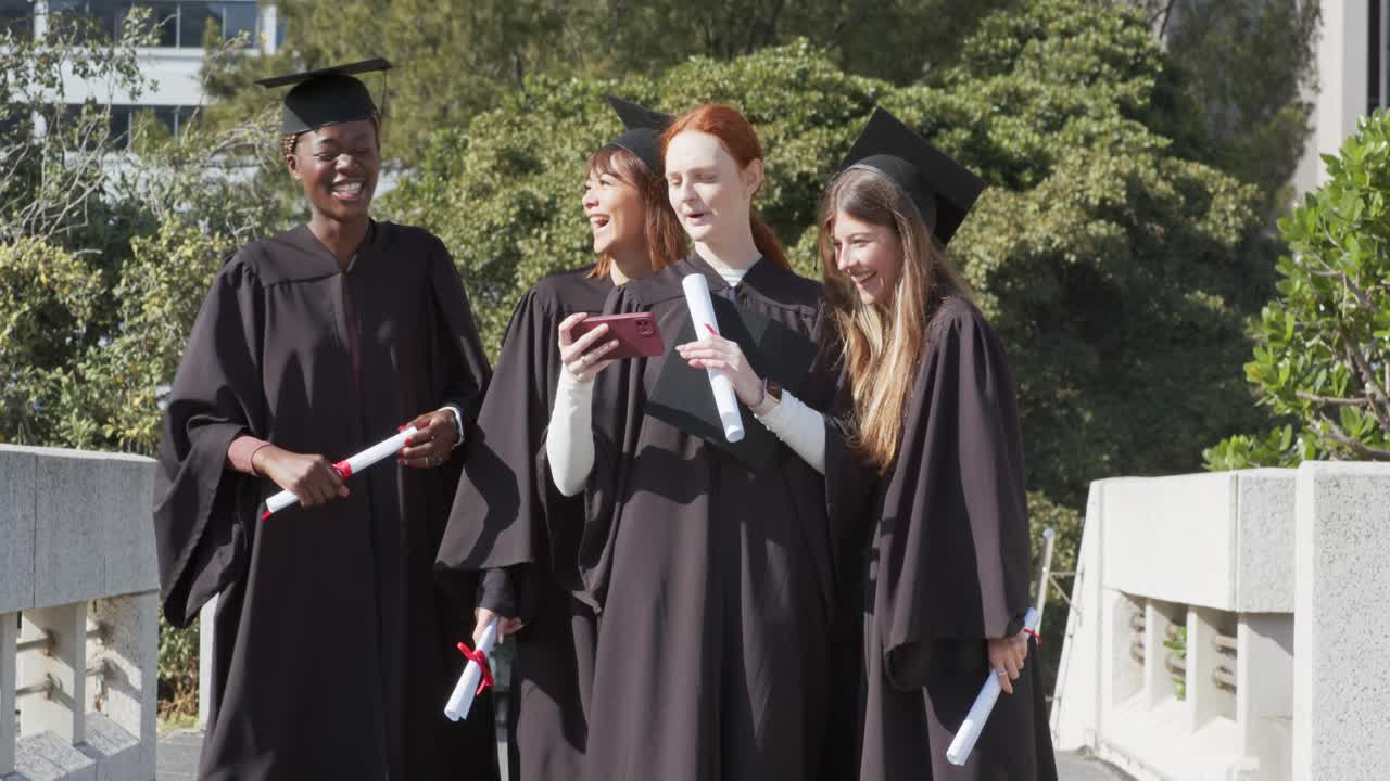 Ulike kvinnelige nyutdannede i kapper som løfter diplomer, tar selfie og feirer på campus