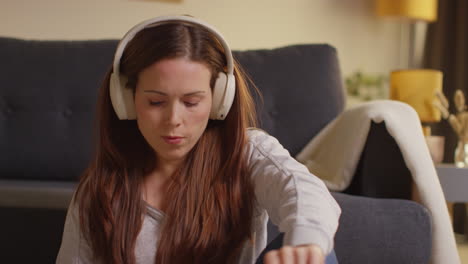 Close-Up-Shot-Of-Woman-Wearing-Wireless-Headphones-Sitting-On-Floor-At-Home-Listening-To-Music