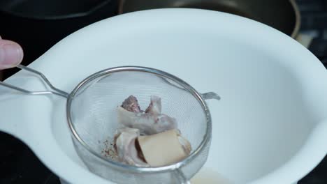 bone broth filtered through a strainer into white bowl