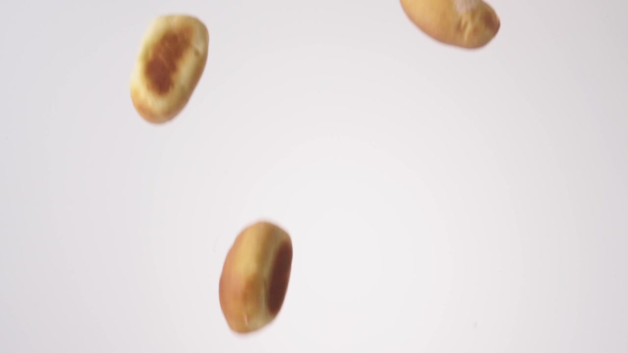 Kolaches salati dorati che piovono su uno sfondo bianco senza soluzione di continuità in slow motion cinematografico. Branding di panetteria texana, reel di antipasti per il giorno della partita, contenuto di finger food per feste.