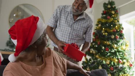 Animation-Eines-Glücklichen-Afroamerikanischen-Seniorenpaares,-Das-Zur-Weihnachtszeit-Geschenke-Teilt