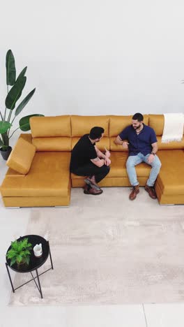aerial perspective: friends engaging in conversation on the couch. talking men on the sofa at home