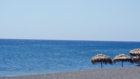 Sun-huts-on-the-clear-beach-on-Santorini-Islands,-Greece