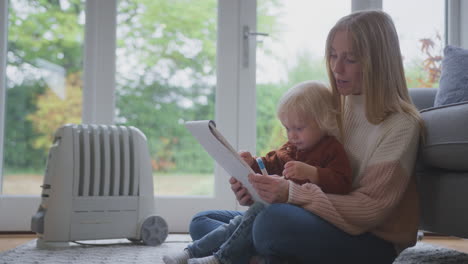 mother and son with plug in radiator drawing picture at home during cost of living energy crisis