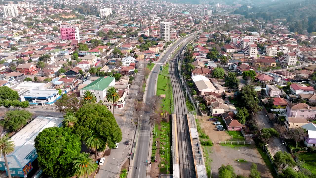 Carrellata aerea sul quartiere di Quilpué con case, Piazza Irarrázabal e il Palazzo del Comune, circondati da palme, Cile
