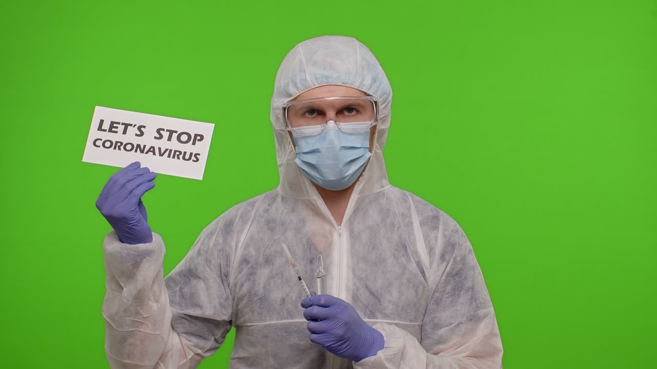 Medical doctor in PPE suit with syringe, ampoule and text on paper - Covid-19 Vaccination Station