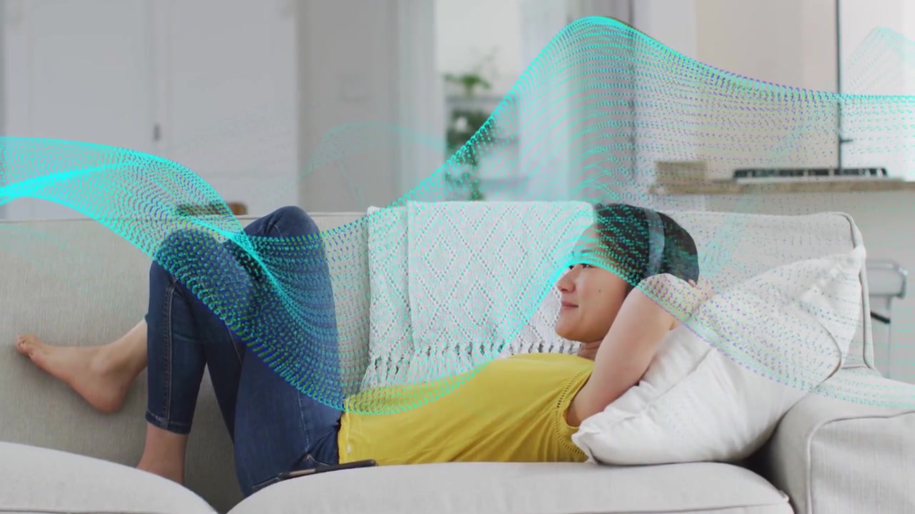 Woman tapping phone, adjusting headphones to listen on sofa, teal audio wave sweeping around her