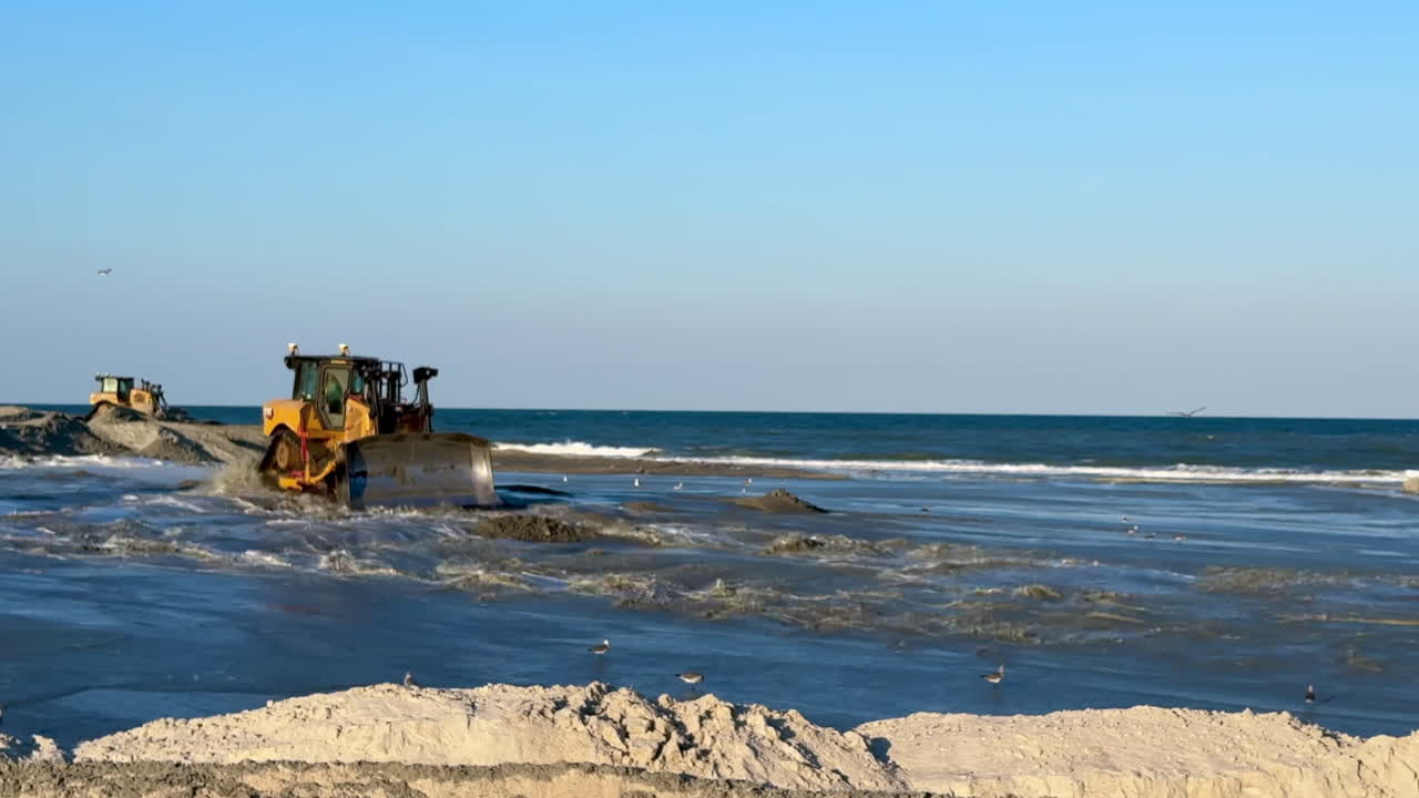 Bulldozer leveling sand and ocean water, beach replenishment, day