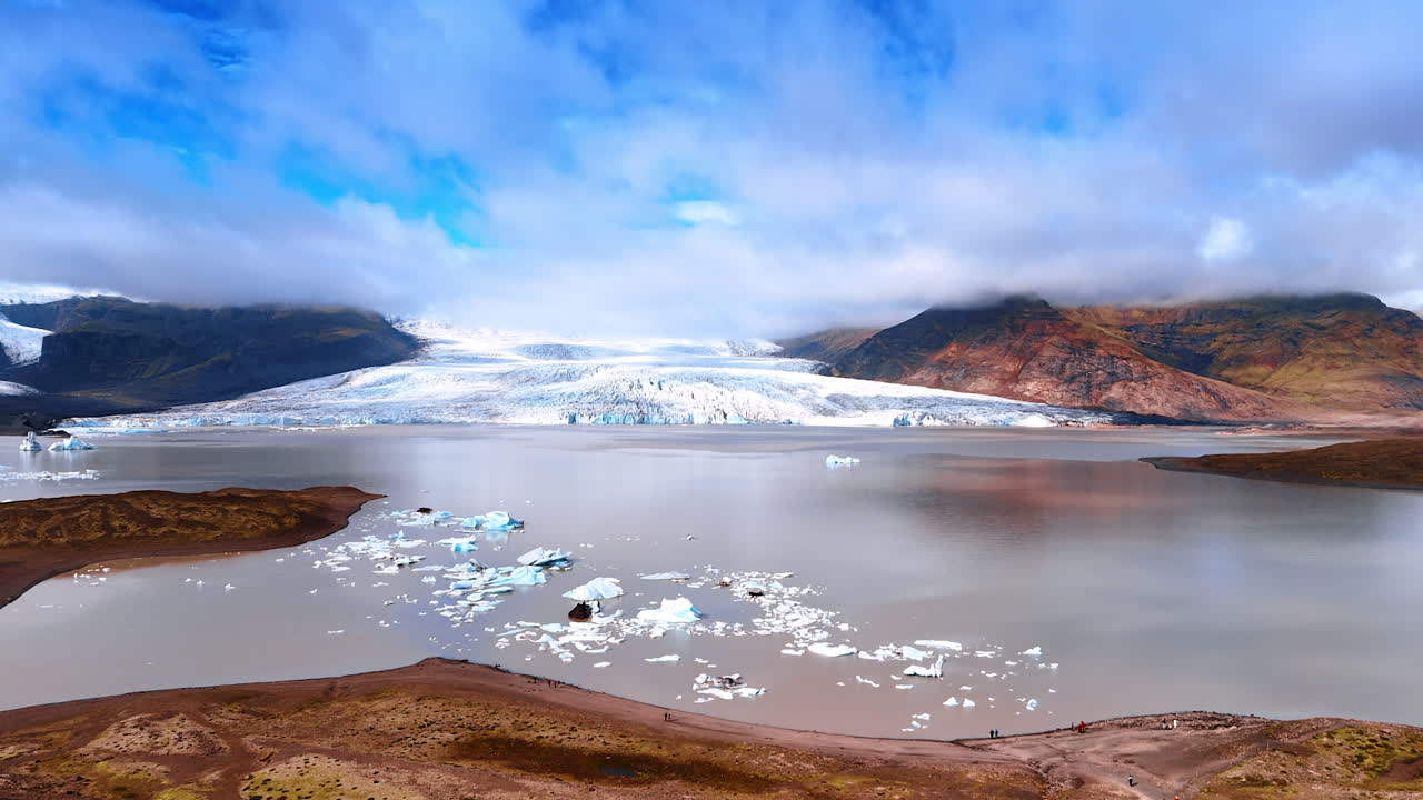 Ancient Iceland glacier descending into the water. Stunning landscape with bare rocks with no vegetation under the cloudy sky.